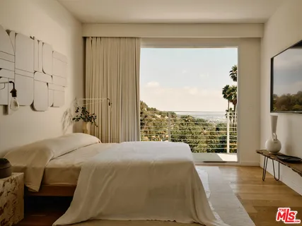 a bedroom with a bed and a flat tv screen next to a window