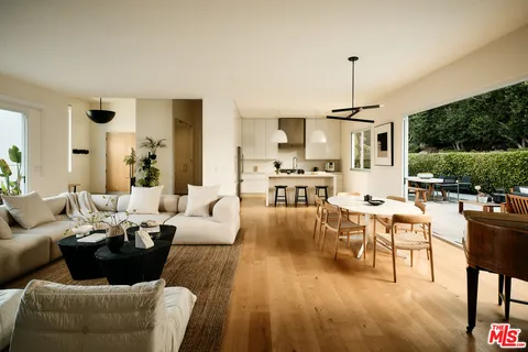 a living room with furniture kitchen view and a large window