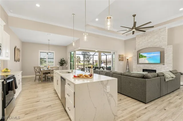 a open kitchen with stainless steel appliances granite countertop a stove and a living room