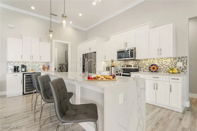 a kitchen with stainless steel appliances granite countertop a stove top oven a refrigerator a sink and white cabinets with wooden floor