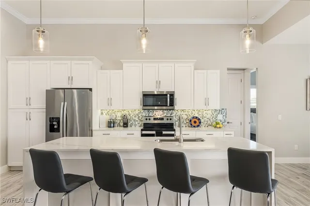 a kitchen with stainless steel appliances a dining table chairs refrigerator and sink