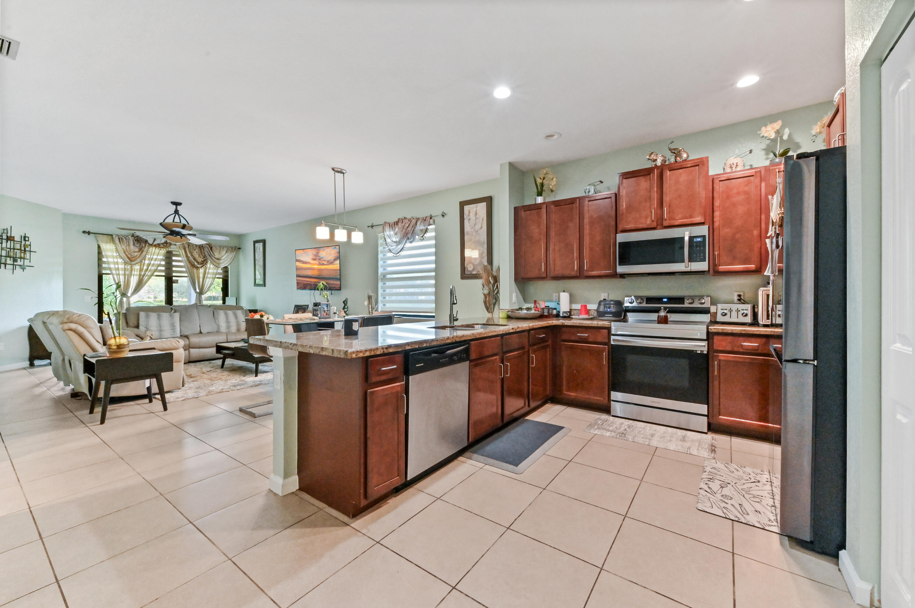 4848 Pond Pine Way Greenacres, FL 33463 - Photo 5 of 14 a large kitchen with stainless steel appliances kitchen island granite countertop a stove a sink dishwasher and a refrigerator with wooden cabinets