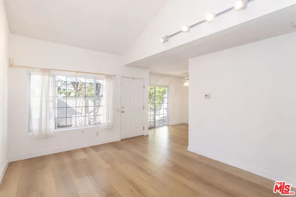 an empty room with wooden floor and windows