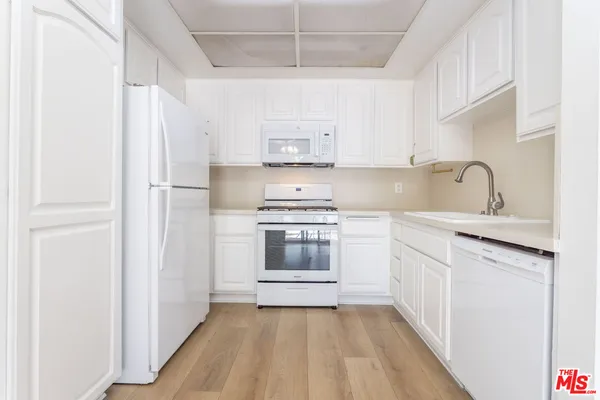 a kitchen with white cabinets and white appliances