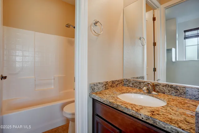 a bathroom with a granite countertop sink mirror toilet and bathtub