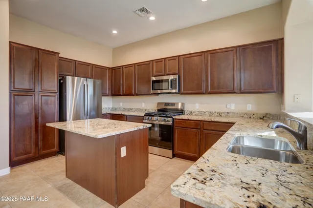 a kitchen with stainless steel appliances granite countertop a stove top oven a refrigerator a sink and dishwasher