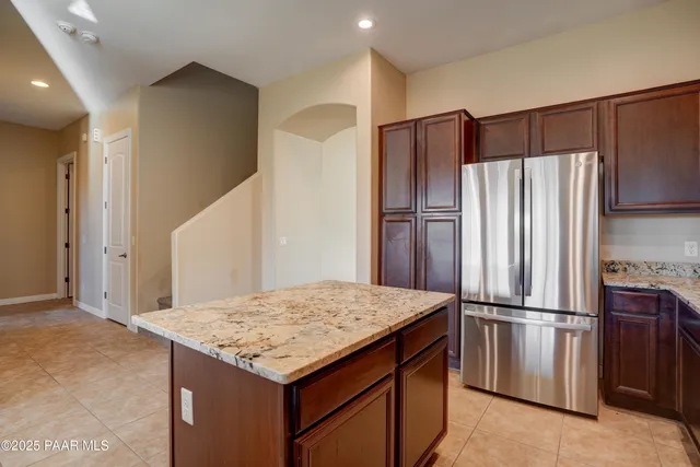 a kitchen with granite countertop a refrigerator and microwave