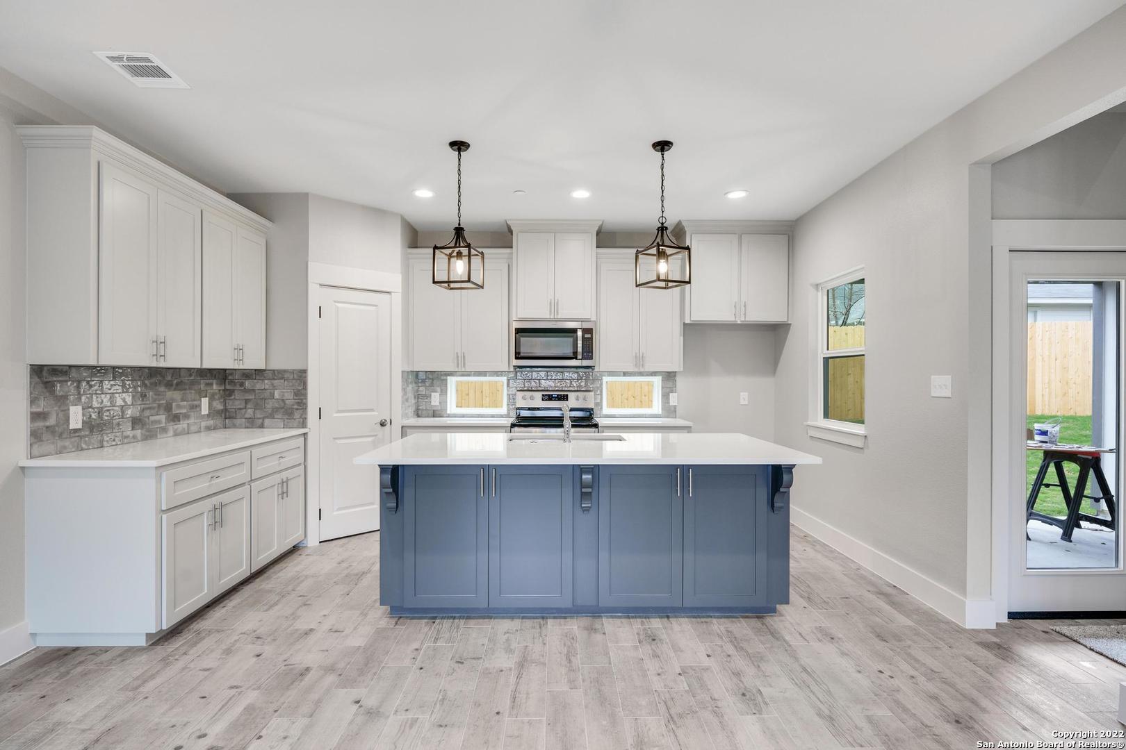 a large kitchen with stainless steel appliances kitchen island granite countertop a sink dishwasher a stove and a refrigerator with wooden floor