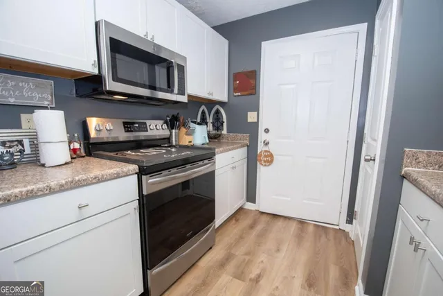 a kitchen with granite countertop cabinets stainless steel appliances and wooden floor