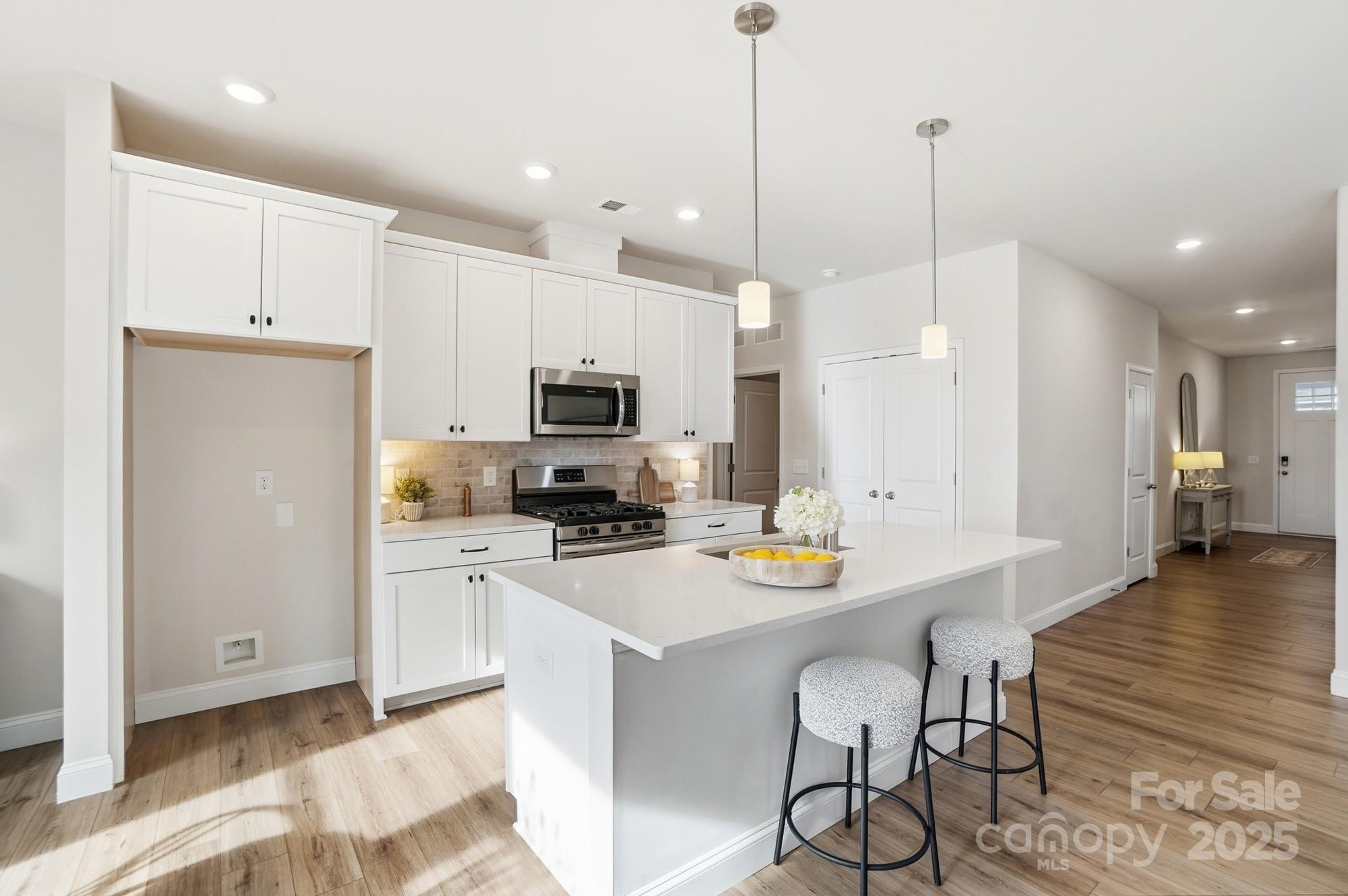 256 Hamrick Road, Unit 12 Cramerton, NC 28056 - Photo 11 of 41 a kitchen with stainless steel appliances kitchen island granite countertop a refrigerator a stove and white cabinets with wooden floor