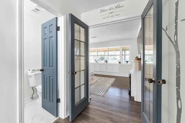 a view of a hallway with wooden floor and a bathroom