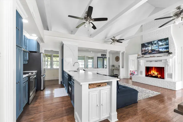 a open kitchen with stainless steel appliances granite countertop a stove oven a sink dishwasher and a fireplace with wooden floor