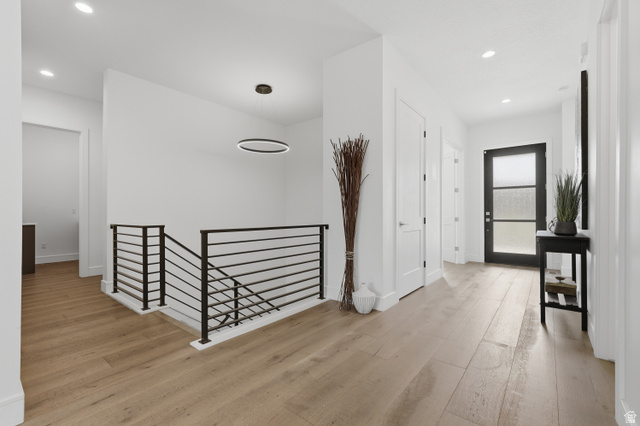 653 East Vandalay Lane Draper, UT 84020 - Photo 7 of 61 Spacious entryway featuring wood-finish flooring, a contemporary black iron stair railing, recessed lighting, and a modern entryway door with frosted glass panels