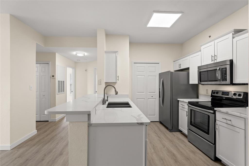 5447 Vineland Road, Unit 1308 Orlando, FL 32811 - Photo 11 of 31 a kitchen with stainless steel appliances a refrigerator stove and sink