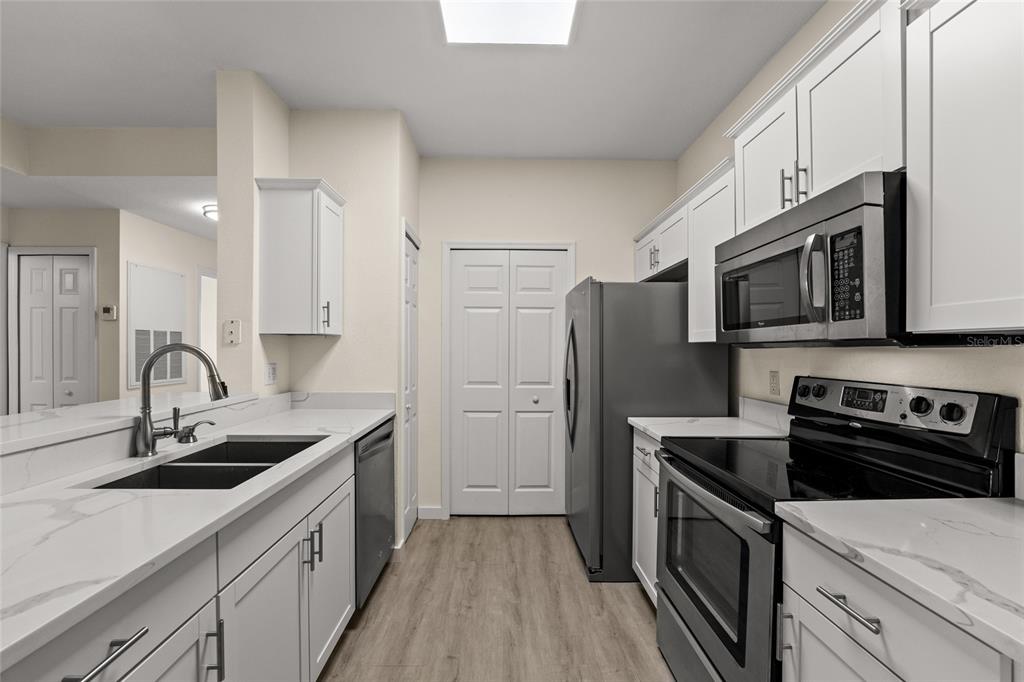 5447 Vineland Road, Unit 1308 Orlando, FL 32811 - Photo 5 of 31 a kitchen with stainless steel appliances granite countertop a sink stove microwave and refrigerator