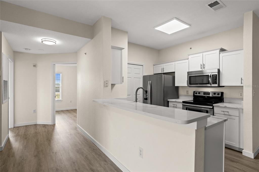 5447 Vineland Road, Unit 1308 Orlando, FL 32811 - Photo 8 of 31 a kitchen with kitchen island a sink stainless steel appliances and cabinets