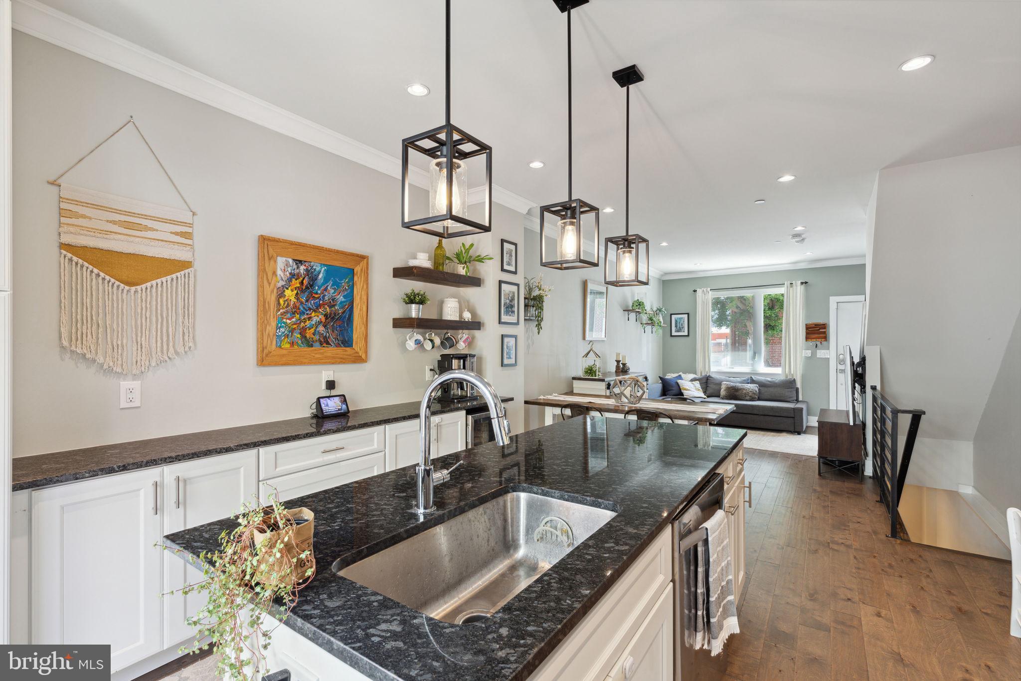 a kitchen with stainless steel appliances granite countertop a sink a counter space and living room view