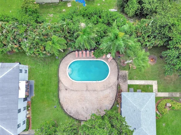an aerial view of a house with outdoor space and trees all around