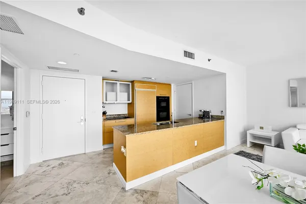 a living room with stainless steel appliances kitchen island granite countertop furniture and a refrigerator