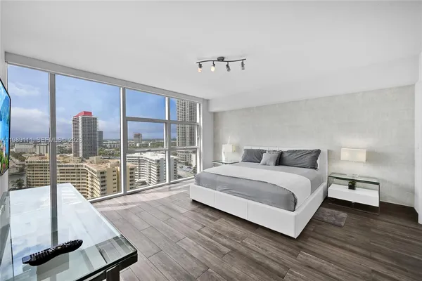 a spacious bedroom with a bed and wooden floor