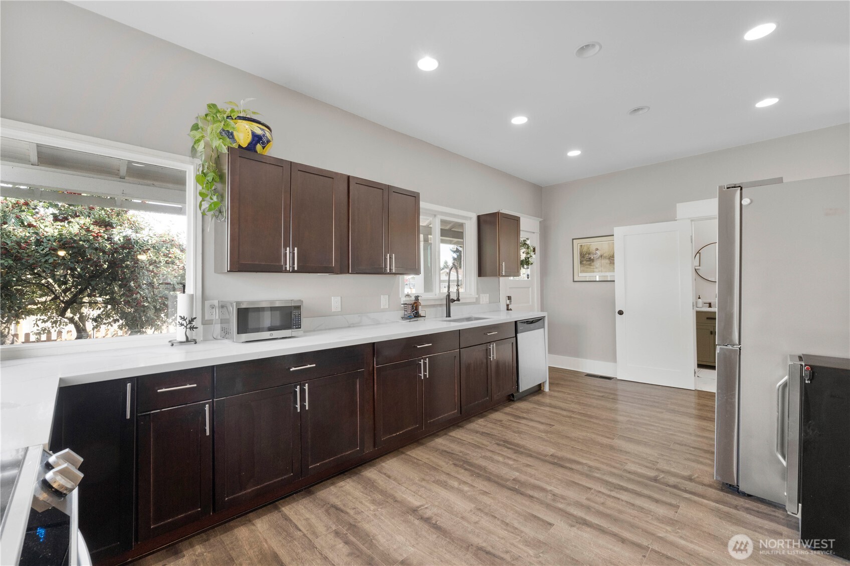 425 Valley Avenue East Sumner, WA 98390 - Photo 12 of 34 a large kitchen with stainless steel appliances granite countertop a refrigerator a sink dishwasher and wooden cabinets with wooden floor