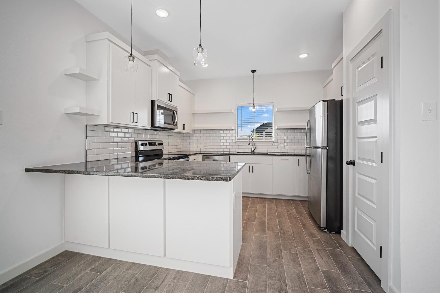 5902 Grinnell Street Lubbock, TX 79416 - Photo 9 of 26 a kitchen with stainless steel appliances granite countertop a sink a stove a refrigerator and island with wooden floor