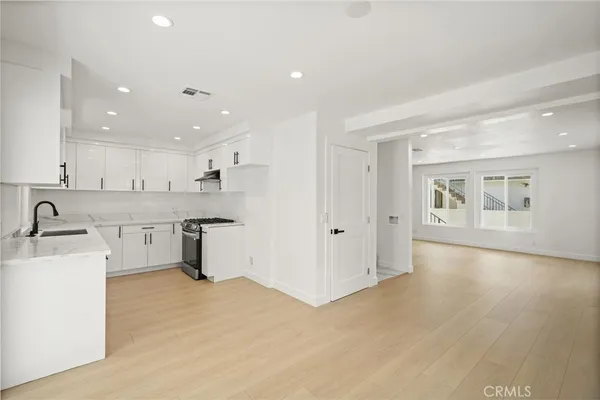 a kitchen with stainless steel appliances granite countertop a sink cabinets and wooden floor