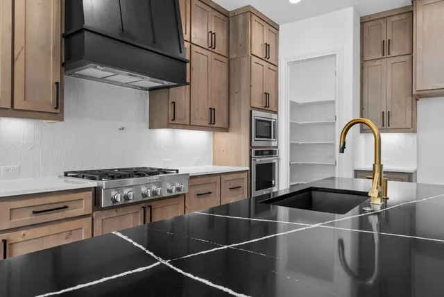 a kitchen with stainless steel appliances granite countertop a sink stove and cabinets