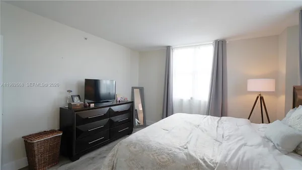 a bedroom with a bed and a flat tv screen on a dresser