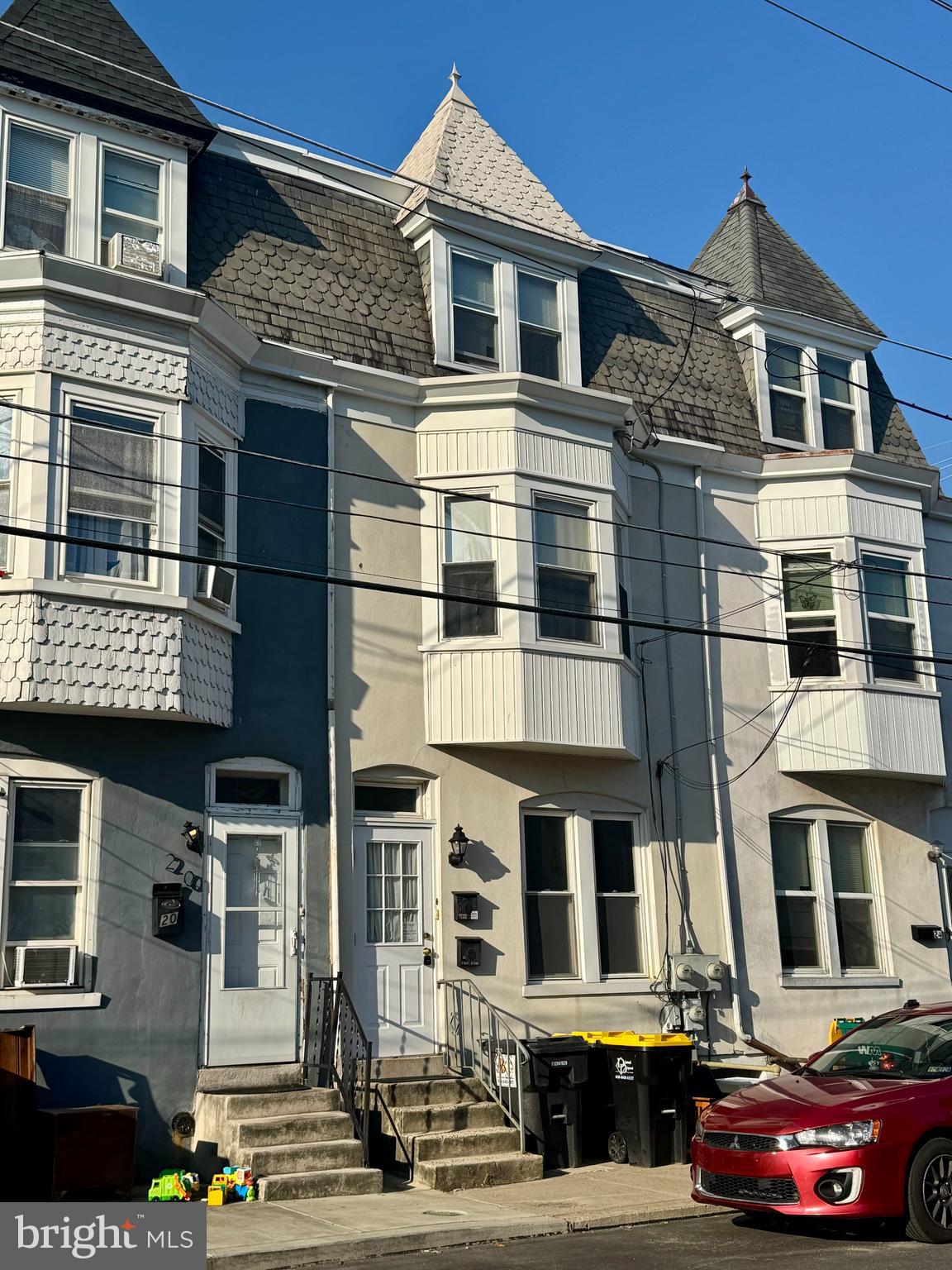 a front view of a building with lot of cars and trees