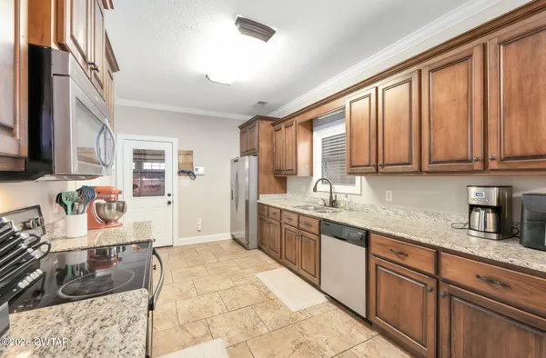a large kitchen with kitchen island granite countertop a sink refrigerator and cabinets