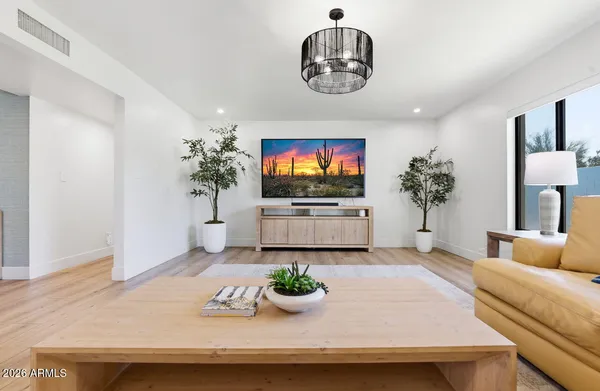 a living room with kitchen and a chandelier
