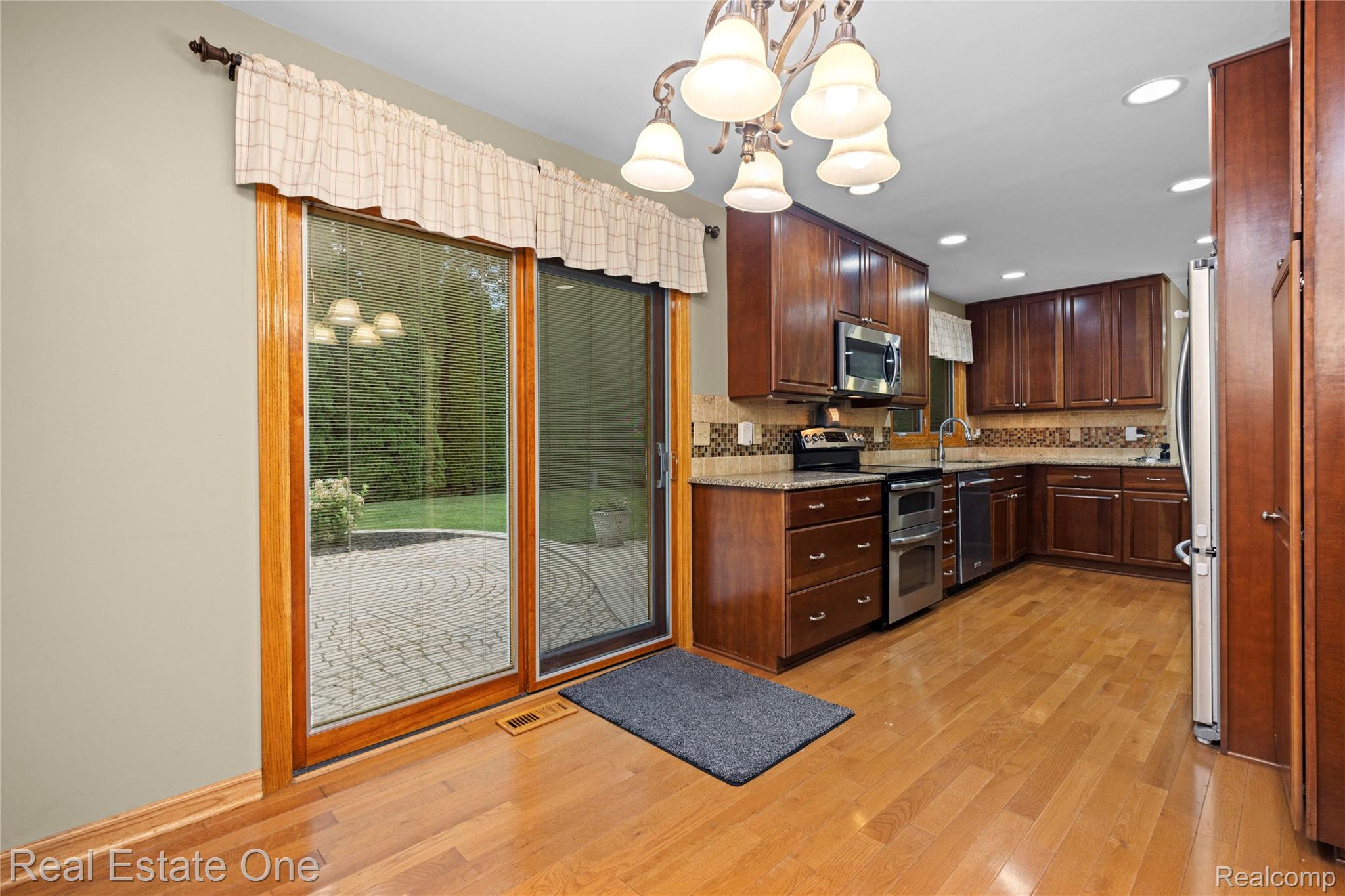 39750 Cheviot Road Canton, MI 48188 - Photo 13 of 71 Kitchen featuring warm wood cabinetry, stainless steel appliances, granite countertops, and wood-finish flooring
