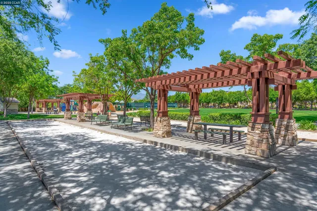 a patio with tables and chairs and a fire pit with large trees