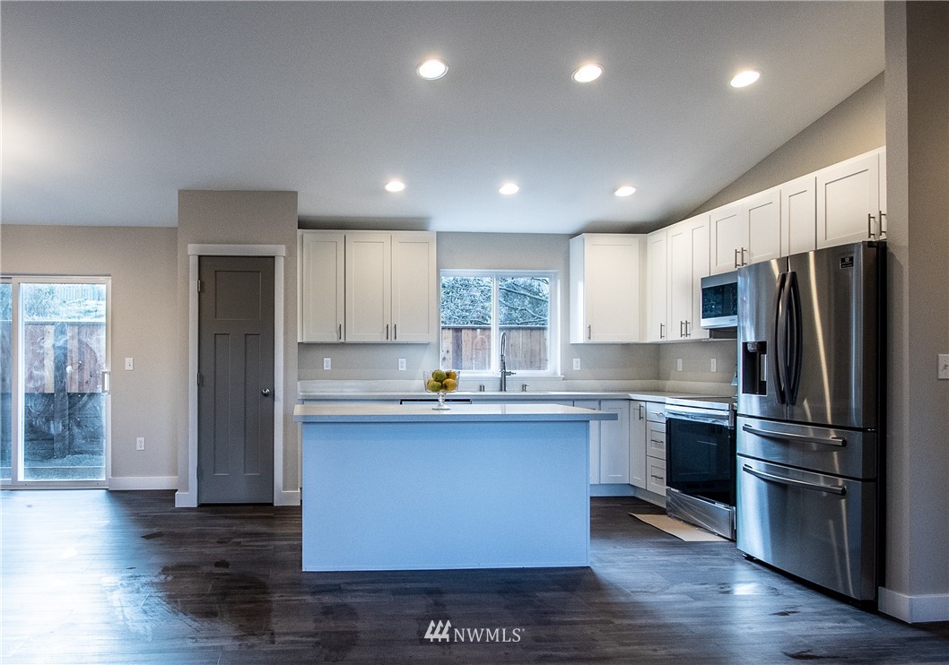5031 East Rasor Road Belfair, WA 98528 - Photo 4 of 16 a kitchen with stainless steel appliances granite countertop a refrigerator a sink dishwasher a stove and white cabinets with wooden floor
