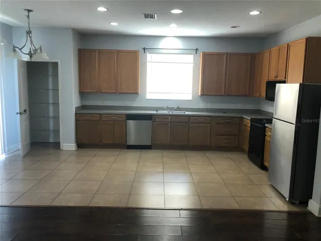 a large kitchen with granite countertop a refrigerator and a stove top oven