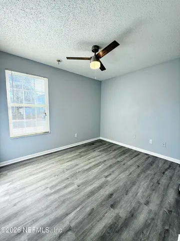 an empty room with wooden floor ceiling fan and windows