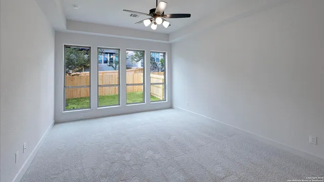 en empty room with windows and ceiling fan