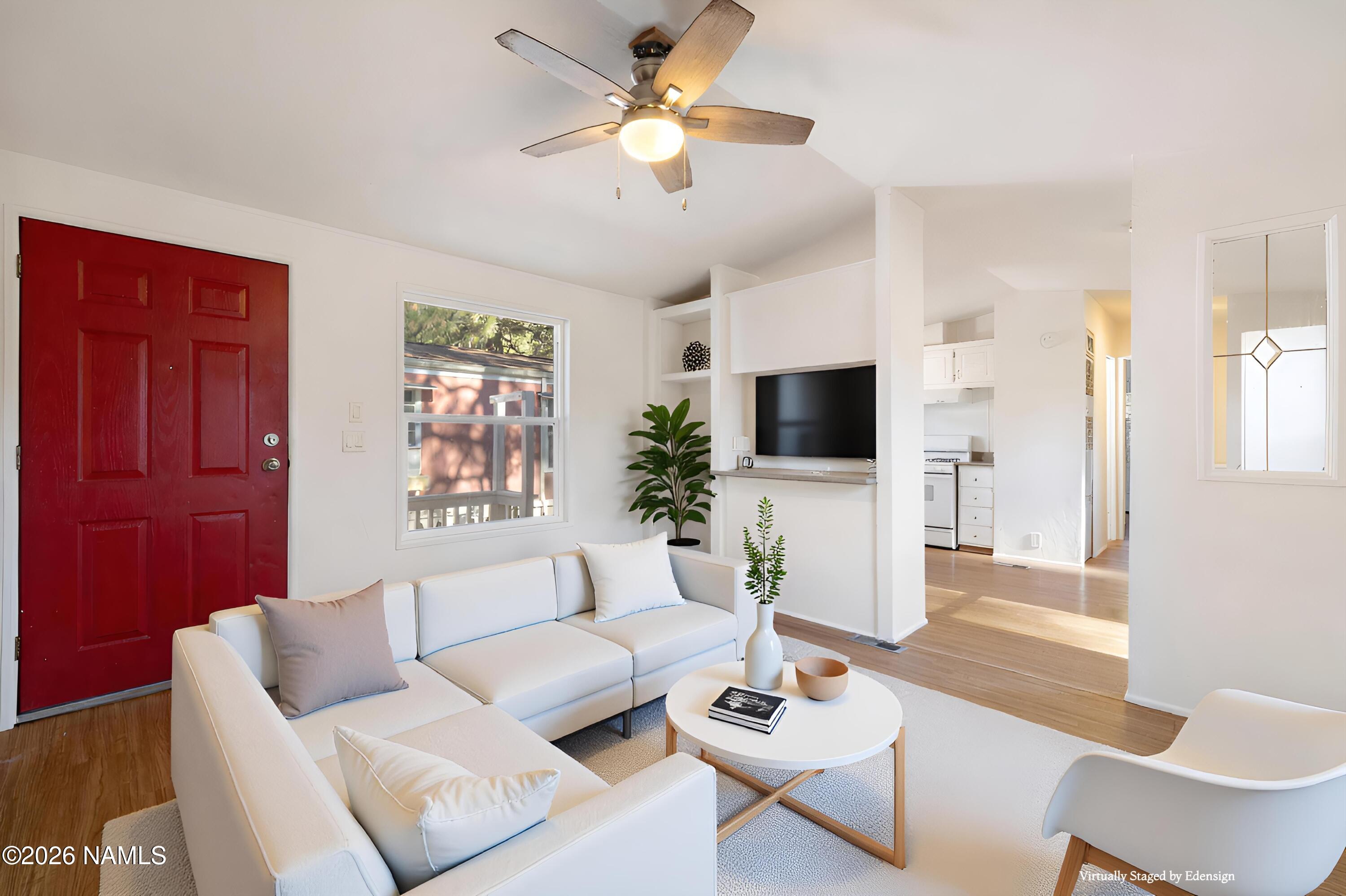 a living room with furniture a flat screen tv and a window