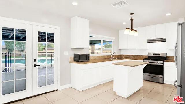 a kitchen with stainless steel appliances granite countertop a refrigerator a stove and a sink