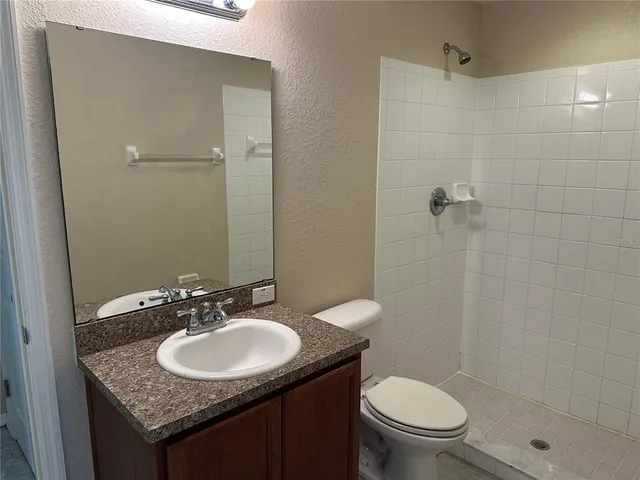 a bathroom with a granite countertop sink toilet and shower