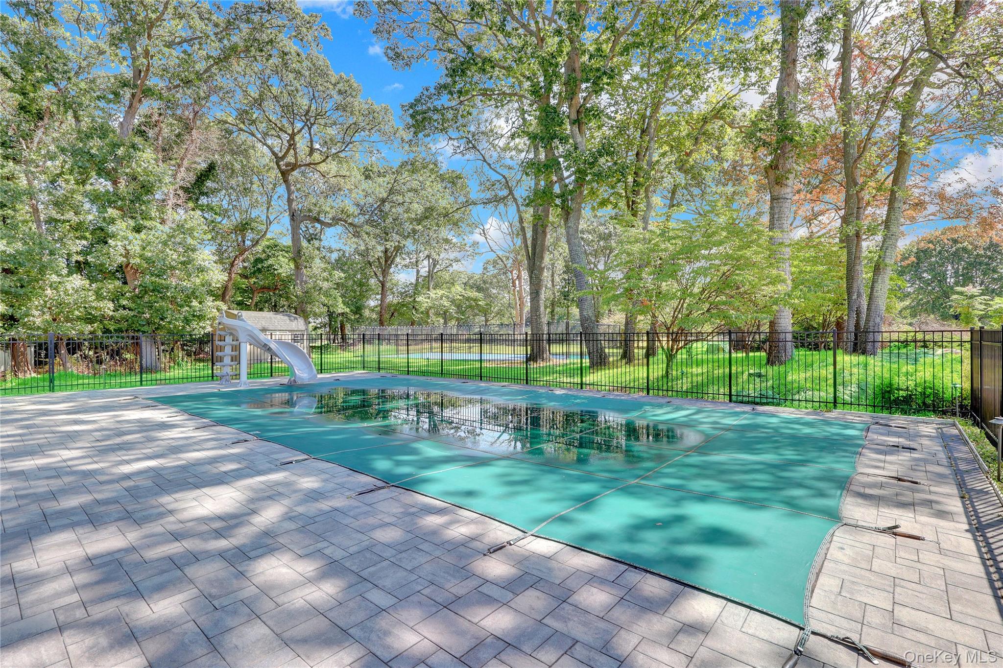 83 Cliff Road Port Jefferson, NY 11777 - Photo 39 of 50 View of pool featuring a water slide, a patio area, and view of wooded area