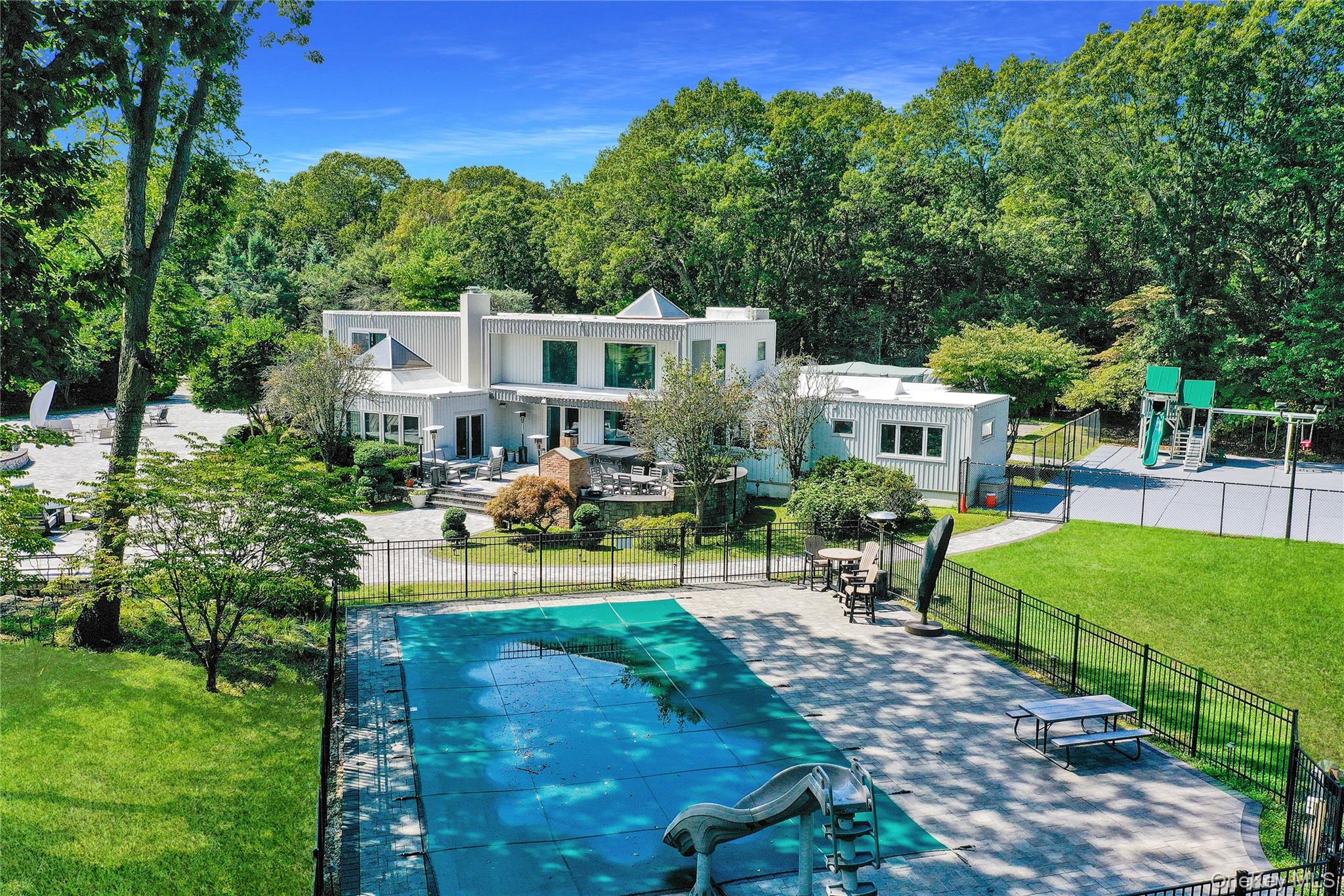 83 Cliff Road Port Jefferson, NY 11777 - Photo 44 of 50 View of pool featuring a patio, a playground, and a view of trees