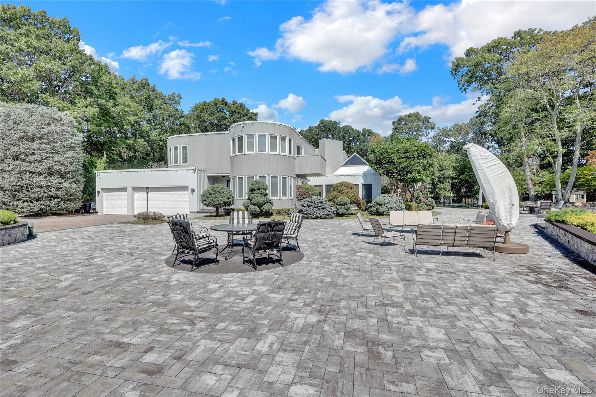 83 Cliff Road Port Jefferson, NY 11777 - Photo 45 of 50 View of patio / terrace with view of wooded area, a garage, and decorative driveway