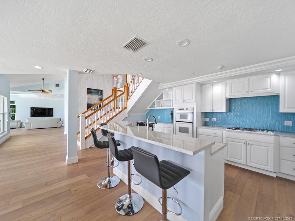 10 Island Road Stuart, FL 34996 - Photo 27 of 60 a kitchen with kitchen island a dining table chairs cabinets and wooden floor