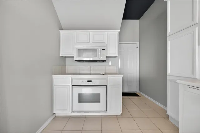 a kitchen with white cabinets and a stove top oven
