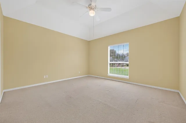 an empty room with a ceiling fan and a window