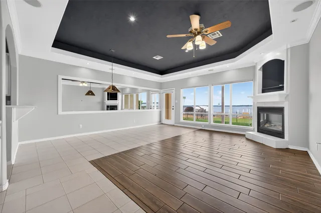a view of an empty room with a fireplace and a chandelier fan