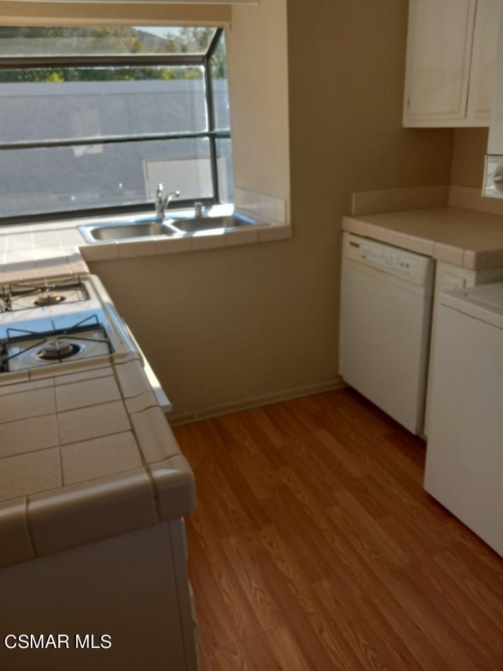 6416 Katherine Road, Unit D Simi Valley, CA 93063 - Photo 3 of 12 a view of a kitchen with wooden floor and white cabinets