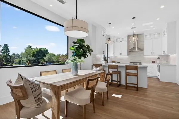 a kitchen with stainless steel appliances granite countertop a refrigerator a sink dishwasher a stove and white cabinets with wooden floor